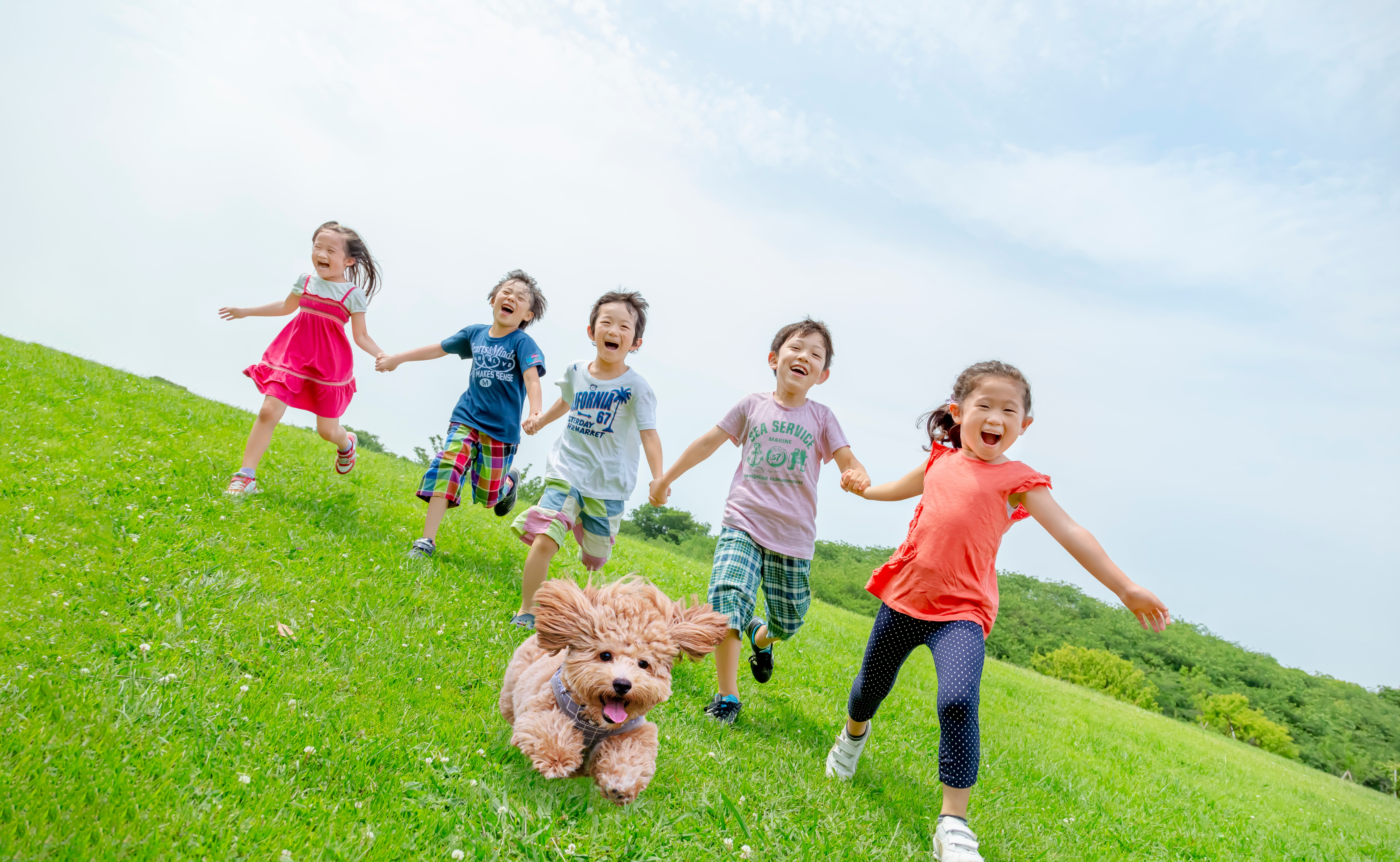 芝生の上を笑顔で走る子どもたち